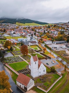 View of a town with church and cemetery surrounded by autumn trees and residential buildings on a