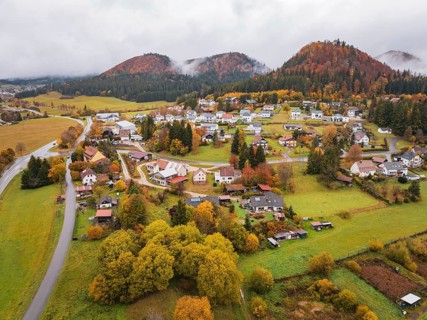 Aerial view of a village surrounded by autumnal hills and clouds of fog, Wehingen, Tuttlingen