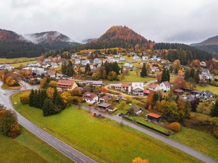 Village nestled in autumnal hills with colorful trees and a curved road, Wehingen, Tuttlingen