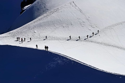 A group of mountaineers runs across a snow-covered mountain, Aiguille du Midi, Chamonix-Mont-Blanc,
