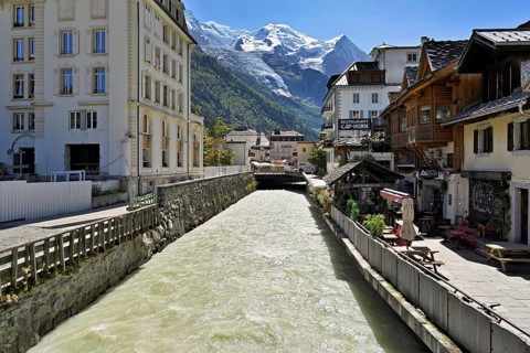 Glacier river Arve flows through the city, with the snow-capped Mont-Blanc mountain range behind,
