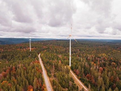 Wind turbines in autumn forest surrounded by clouds and roads, Simmersfeld wind farm, Germany