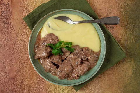 Liver beef stroganoff with mashed potatoes, table setting in green tones, homemade