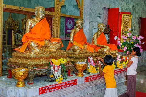 Buddhist believers Buddhists pray making offerings to statues of Buddhist monks covered with gold