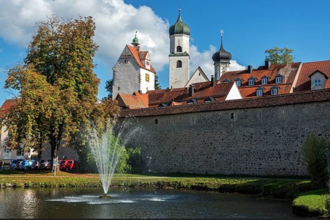 Trench pond with water fountain, city wall, church towers and water tower at the back, Isny,