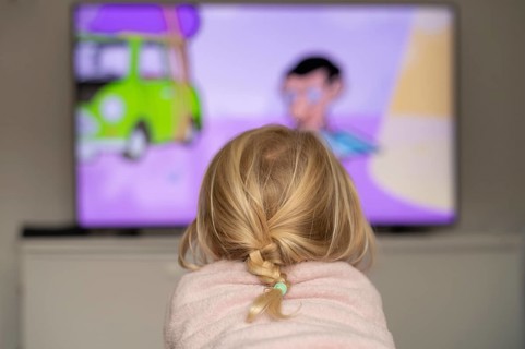 Child, girl, 4 years old, blonde, lying on sofa, watching TV, watching television, in front of