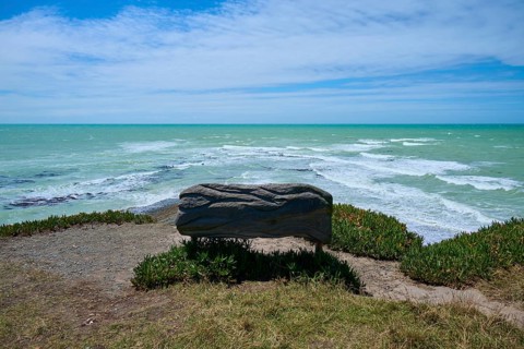 Wooden bench with sea view under cloudy sky, Tuhawaiki Point Lighthouse or Jack's Point Lighthouse,