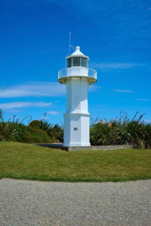 White lighthouse in a meadow next to the coast, Tuhawaiki Point Lighthouse or Jack's Point