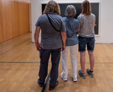Three visitors look at a painting in an exhibition, Bavaria, Germany