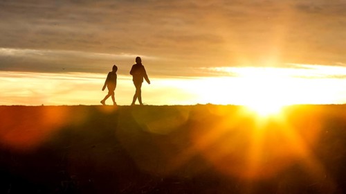 Woman and child walk across a dike on the island of Fehmarn at sunset, 13.10.2025, Fehmarn,