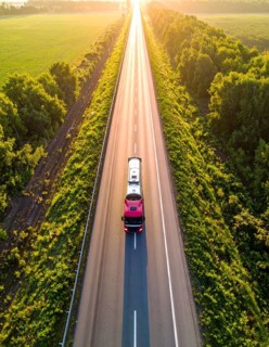 Petrol cargo truck lorry tanker driving on highway hauling oil products at sunrise, wide hilly