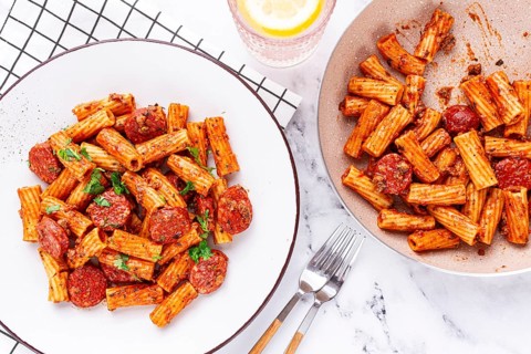 Rigatoni pasta with spicy sausage, and rich tomato sauce served, on a white plate, homemade
