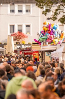 Busy shopping street in autumn, people strolling between modern buildings and colorful shops,