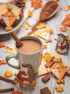 Cup of hot chocolate with cinnamon stick and autumn animal decorations