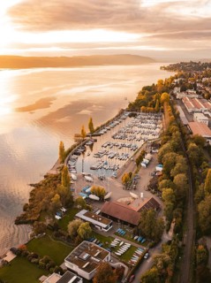 A harbor with anchored boats at sunset, surrounded by an urban landscape in autumn, Überlingen,