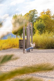 Child swings on a playground in autumn surrounded by colorful trees, Überlingen, Lake Constance,