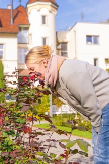 Woman with red hair enjoying the scent of flowers in autumn garden, Überlingen, Lake Constance,