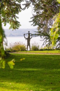 A statue in a park surrounded by trees and green grass with an autumnal atmosphere, Überlingen,