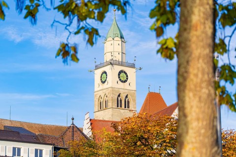 Church tower against blue sky with autumn leaves in the foreground, Überlingen, Lake Constance,