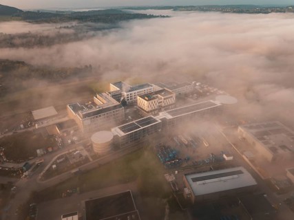 Building in an industrial area seen from above in fog, surrounded by landscape at daybreak, new