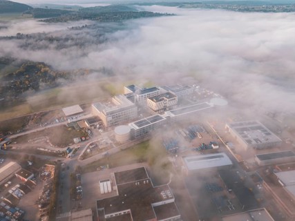 Wide angle view of an industrial center in fog surrounded by natural landscape at dawn, new