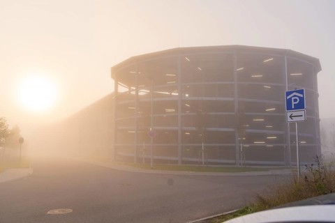 Misty street with parking garage at sunrise, mystical atmosphere, new hospital health campus
