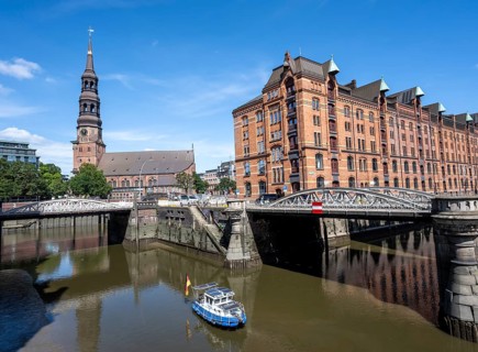 Boat on the Kleines Fleet canal with Kannengießer bridge and tower of the main church of St.