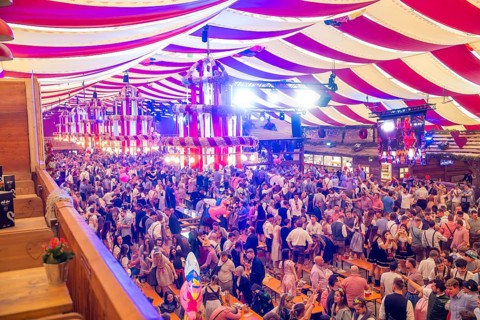 Fully occupied marquee with people in traditional costumes and colourful decorations, Cannstatter