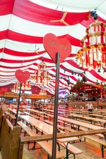Festively decorated marquee with red blankets, wooden benches and heart-shaped sign, Cannstatter