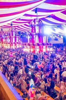 Marquee full of people in traditional Bavarian traditional costume with colourful lighting and