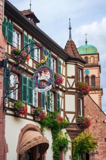 Decorated half-timbered house with guild sign of a patisserie in the old town centre of Kaysersberg