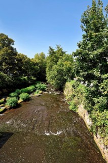 Ettlingen, Germany - August 13th 2025: Alb river flowing through Ettlingen in summer with trees and