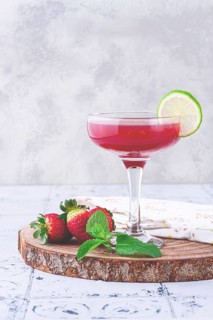 Refreshing cocktail in an elegant glass with lime and strawberries, sunshine, no people