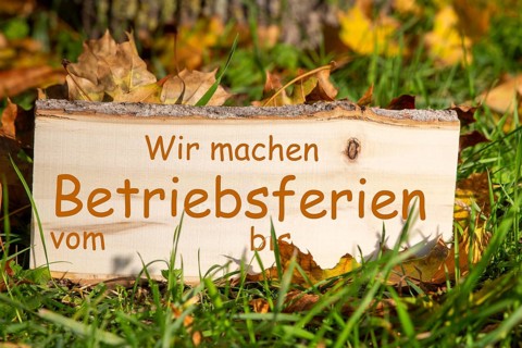 Company holidays autumn: Wooden sign with added text WIR MACHEN BETRIEBSFERIEN VOM/BIS in a meadow