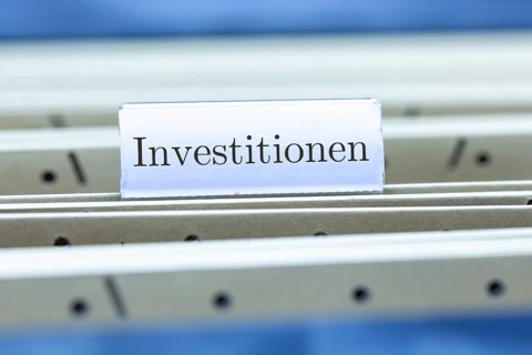 (Photomontage) Sign with the inscription INVESTMENTS on a suspension file folder