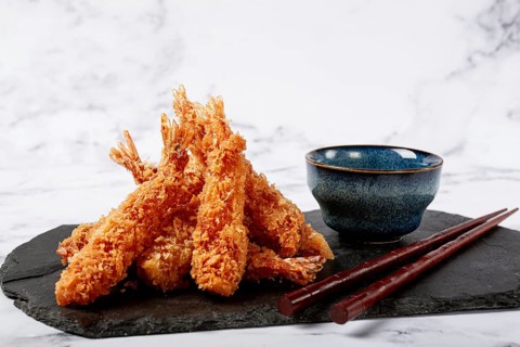 Shrimp in tempura, deep fried, on black slate, with sauce, light marble table, no people