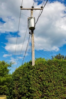Electricity transformer, high voltage transmission wires, internet, telephone cables attached to