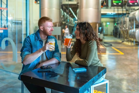 Couple sitting at a table in a modern craft beer factory, drinking and communicating while enjoying