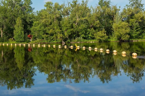 String of yellow cautionary navigation marker buoys on water surafce of river serving to warn,