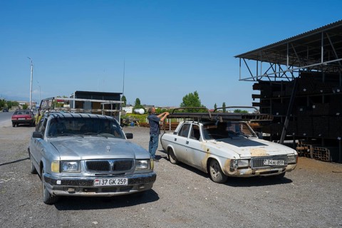 Two rusty old cars, a man in the background, mid-range cars GAZ-3110 Volga and GAZ-24 Volga,