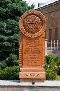 An elaborately engraved stone khachkar with complex ornaments and Armenian characters, surrounded