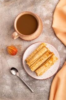 Waffles with caramel on brown concrete background and orange linen textile, cup of coffee, top