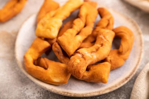 Crunchy biscuit Brushwood cookies sprinkled with powdered sugar on brown concrete background and