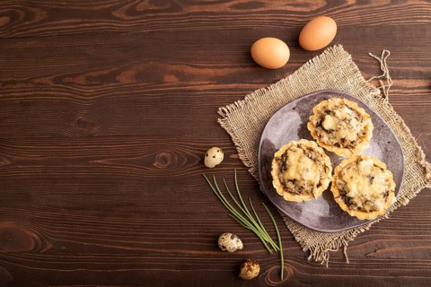 Tartlets with meat and cheese on brown wooden background and linen textile. top view, flat lay,