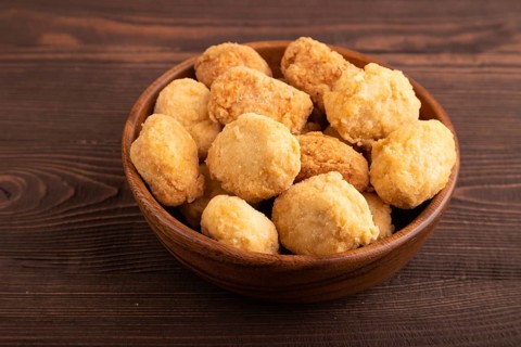 Fried crispy Chicken Nuggets on brown wooden background. side view, close up