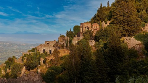 Church of Agia Sophia from the 14th century AD, ruins and trees cover a sunny hillside with a clear