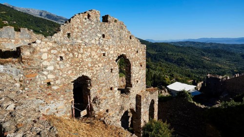 Ruins on a hill overlooking a vast mountain landscape under a clear blue sky, Mystras, Mistra,