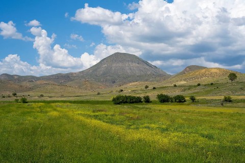 Mountain landscape with vast green and yellow fields under a cloudy sky, landscape near Shaghap,
