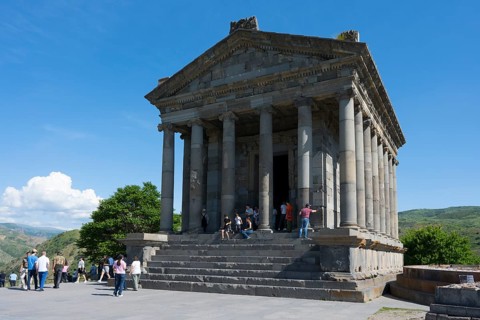 Ancient temple with visitors, surrounded by green nature and stone structures, Greek-Roman Temple