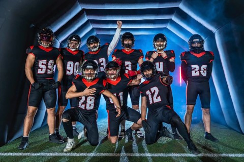 American football team players posing confidently with a victorious gesture, emerging from a